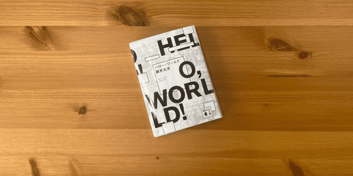 「HELLO, WORLD!」の本が木のテーブルに置かれている